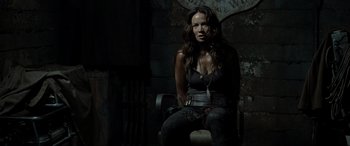 Movie still from “Terminator Salvation” (2009), directed by McG – A woman sitting on a chair in a dark room; Medium shot, Over the shoulder angle