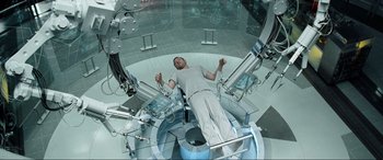 Movie still from “Terminator Salvation” (2009), directed by McG – A man laying on a bed in a room; Wide shot, Overhead angle