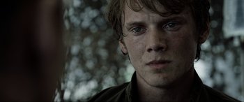 Movie still from “Terminator Salvation” (2009), directed by McG – A young man's face in front of trees; Close Up shot, Over the shoulder angle