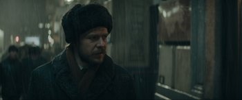 Movie still from “Tetris” (2023), directed by Jon S. Baird – A man wearing a fur hat and a coat; Close Up shot, Over the shoulder angle
