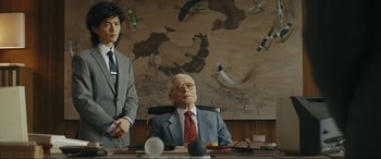 Movie still from “Tetris” (2023), directed by Jon S. Baird – An older man sitting at a desk in front of a map; Medium shot, Low angle