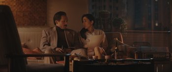 Movie still from “Tetris” (2023), directed by Jon S. Baird – A man and a woman are sitting on a couch; Medium shot, Over the shoulder angle