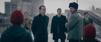 Movie still from “Tetris” (2023), directed by Jon S. Baird – A group of men standing next to each other on the street; Medium shot, Over the shoulder angle