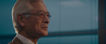 Movie still from “Tetris” (2023), directed by Jon S. Baird – An older man wearing glasses looking off into the distance; Close Up shot, Low angle