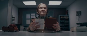 Movie still from “Tetris” (2023), directed by Jon S. Baird – A woman in a military uniform holding an envelope and a passport; Close Up shot, Low angle