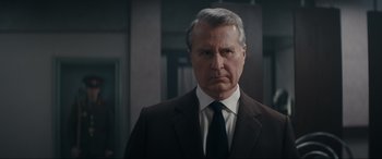 Movie still from “Tetris” (2023), directed by Jon S. Baird – A man in a suit and tie standing in front of a building; Close Up shot, Low angle