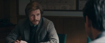 Movie still from “Tetris” (2023), directed by Jon S. Baird – A man sitting at a table in front of a map; Close Up shot, Over the shoulder angle