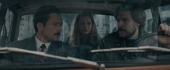 Movie still from “Tetris” (2023), directed by Jon S. Baird – A group of people sitting in the back of a car; Close Up shot, Over the shoulder angle