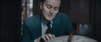 Movie still from “Tetris” (2023), directed by Jon S. Baird – A man wearing a suit and tie looking at a map; Close Up shot, High angle