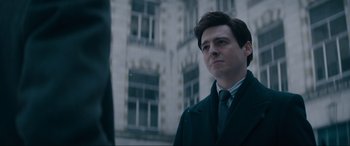 Movie still from “Tetris” (2023), directed by Jon S. Baird – A man wearing a suit and tie standing in front of a building; Close Up shot, Low angle