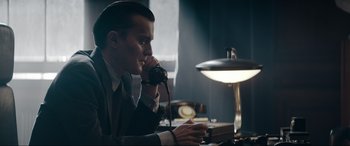 Movie still from “Tetris” (2023), directed by Jon S. Baird – A man sitting at a desk talking on a phone; Medium shot, Low angle