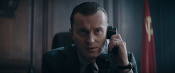 Movie still from “Tetris” (2023), directed by Jon S. Baird – A man in a business suit talking on a phone; Close Up shot, Low angle