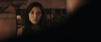 Movie still from “Tetris” (2023), directed by Jon S. Baird – A woman with long black hair looking at the camera; Close Up shot, Over the shoulder angle