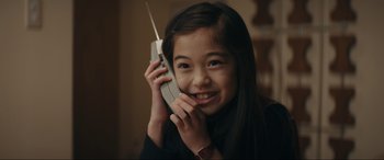 Movie still from “Tetris” (2023), directed by Jon S. Baird – A young girl holding a cell phone up to her ear; Close Up shot, High angle