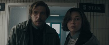 Movie still from “Tetris” (2023), directed by Jon S. Baird – A man and a woman standing next to each other in a room; Medium shot, Low angle