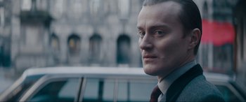 Movie still from “Tetris” (2023), directed by Jon S. Baird – A person wearing a suit and tie; Close Up shot, Over the shoulder angle