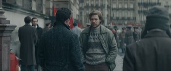 Movie still from “Tetris” (2023), directed by Jon S. Baird – Two men standing on the sidewalk talking to each other; Medium shot, Over the shoulder angle