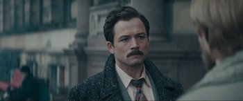 Movie still from “Tetris” (2023), directed by Jon S. Baird – A man with a mustache wearing a suit and tie; Close Up shot, Over the shoulder angle