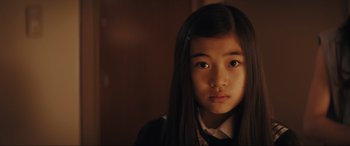 Movie still from “Tetris” (2023), directed by Jon S. Baird – A young girl with long black hair wearing a school uniform; Close Up shot, High angle