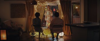 Movie still from “Tetris” (2023), directed by Jon S. Baird – Two people sitting in front of a woman in a kimono; Wide shot, Low angle