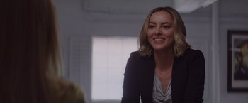 Movie still from “That's Amor” (2022), directed by Shaun Paul Piccinino – A woman in a black jacket smiling for the camera; Close Up shot, Over the shoulder angle