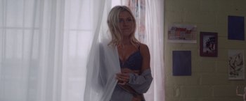 Movie still from “That's Amor” (2022), directed by Shaun Paul Piccinino – A beautiful blonde woman in a blue bra and a white robe; Medium shot, Low angle