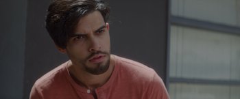 Movie still from “That's Amor” (2022), directed by Shaun Paul Piccinino – A person wearing a red shirt; Close Up shot, Over the shoulder angle