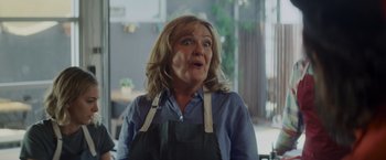 Movie still from “That's Amor” (2022), directed by Shaun Paul Piccinino – A woman in an apron is looking surprised; Close Up shot, Low angle