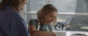 Movie still from “That's Amor” (2022), directed by Shaun Paul Piccinino – A woman wearing an apron looking down at a piece of paper; Close Up shot, Over the shoulder angle