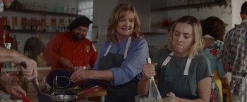 Movie still from “That's Amor” (2022), directed by Shaun Paul Piccinino – A group of people in a kitchen preparing food; Medium shot, Low angle