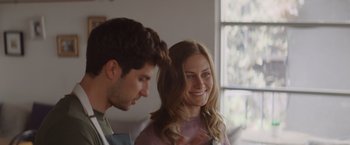 Movie still from “That's Amor” (2022), directed by Shaun Paul Piccinino – A man and a woman smiling at each other in front of a window; Close Up shot, Over the shoulder angle
