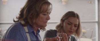 Movie still from “That's Amor” (2022), directed by Shaun Paul Piccinino – A woman and a girl are looking at something in her hand; Close Up shot, Over the shoulder angle