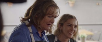 Movie still from “That's Amor” (2022), directed by Shaun Paul Piccinino – Two women wearing aprons are standing next to each other; Close Up shot, Over the shoulder angle