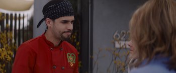 Movie still from “That's Amor” (2022), directed by Shaun Paul Piccinino – A man in a red shirt and a black head band; Close Up shot, Over the shoulder angle