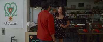 Movie still from “That's Amor” (2022), directed by Shaun Paul Piccinino – Two people standing in front of each other in front of a counter; Medium shot, Over the shoulder angle