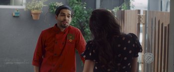 Movie still from “That's Amor” (2022), directed by Shaun Paul Piccinino – A man and a woman are talking in front of a mirror; Medium shot, Over the shoulder angle