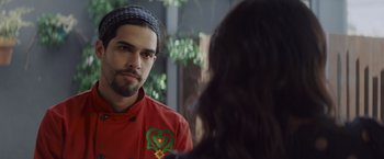 Movie still from “That's Amor” (2022), directed by Shaun Paul Piccinino – A man in a red shirt is talking to a woman in front of a mirror; Close Up shot, Over the shoulder angle