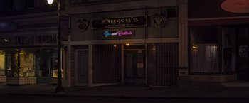 Movie still from “That's Amor” (2022), directed by Shaun Paul Piccinino – A building that is lit up at night time; Wide shot, High angle