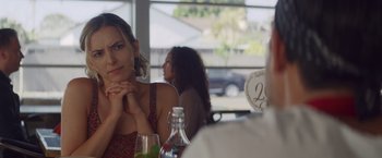 Movie still from “That's Amor” (2022), directed by Shaun Paul Piccinino – A woman sitting at a table with a glass of wine; Close Up shot, Over the shoulder angle