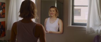 Movie still from “That's Amor” (2022), directed by Shaun Paul Piccinino – A woman looking at her reflection in a mirror; Close Up shot, Over the shoulder angle