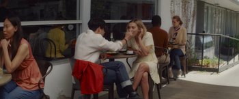 Movie still from “That's Amor” (2022), directed by Shaun Paul Piccinino – A man and a woman sitting at an outdoor table; Medium shot, Over the shoulder angle