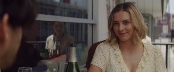 Movie still from “That's Amor” (2022), directed by Shaun Paul Piccinino – A beautiful young lady sitting in front of a window with a glass of wine; Close Up shot, Over the shoulder angle