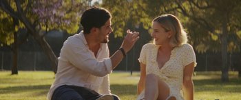 Movie still from “That's Amor” (2022), directed by Shaun Paul Piccinino – A man and a woman sitting in the grass; Medium shot, Over the shoulder angle