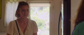 Movie still from “That's Amor” (2022), directed by Shaun Paul Piccinino – A woman standing next to a window in a room; Close Up shot, Over the shoulder angle