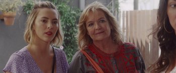 A woman standing next to another woman in front of a building