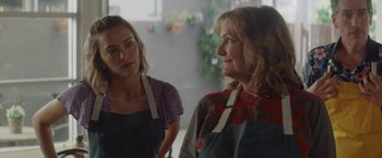 Movie still from “That's Amor” (2022), directed by Shaun Paul Piccinino – Two women in aprons standing next to each other in a kitchen; Close Up shot, Over the shoulder angle