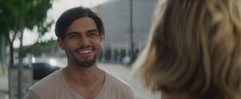 Movie still from “That's Amor” (2022), directed by Shaun Paul Piccinino – A man with long hair smiling at a woman with blonde hair; Close Up shot, Over the shoulder angle