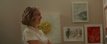 Movie still from “That's Amor” (2022), directed by Shaun Paul Piccinino – A woman standing in front of some paintings; Close Up shot, Over the shoulder angle
