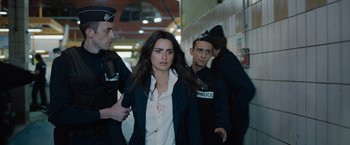 Movie still from “The 355” (2022), directed by Simon Kinberg – A woman in a white shirt and a police officer; Medium shot, Over the shoulder angle