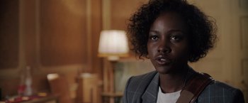 Movie still from “The 355” (2022), directed by Simon Kinberg – A person wearing a suit jacket; Close Up shot, Over the shoulder angle